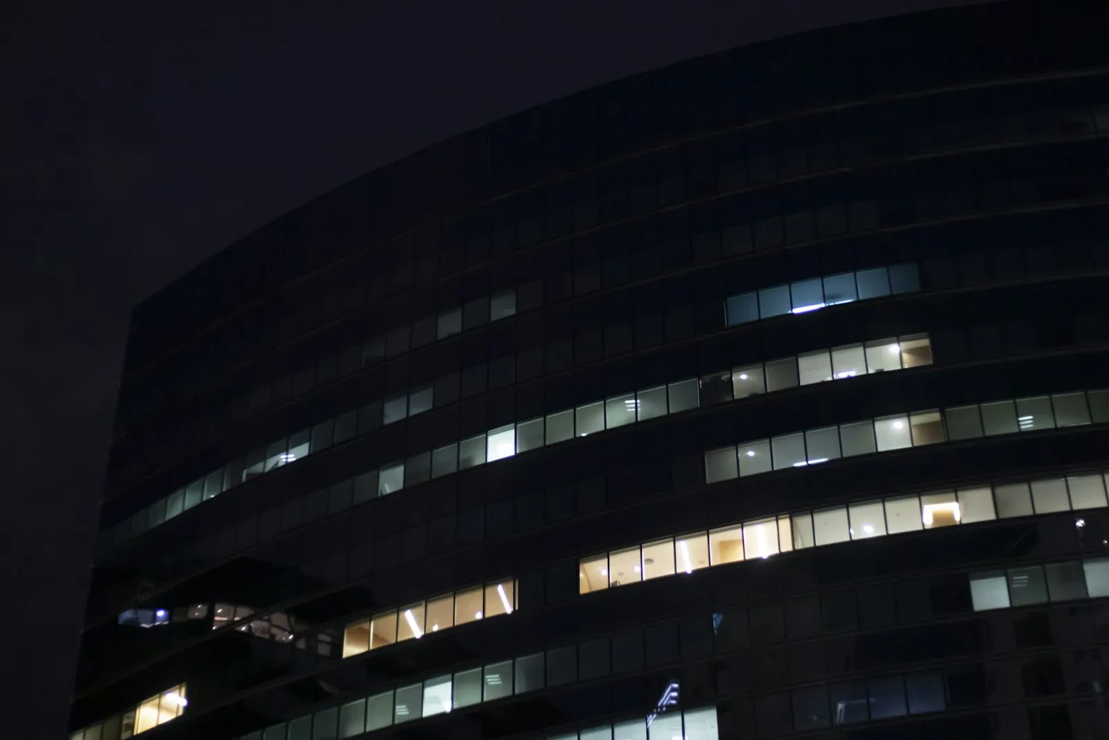 A modern office building at night, its windows lit against the dark sky